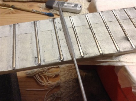 Reducción de las aristas de los trastes para preparar el coronamiento.